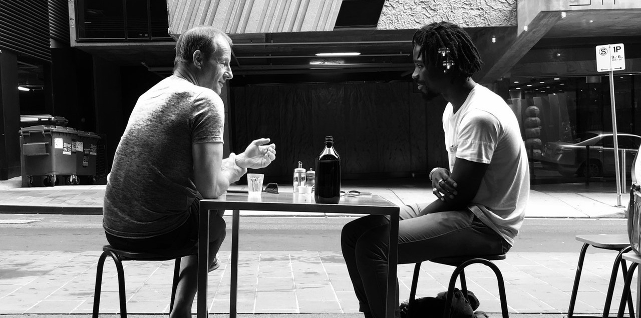 two men talking at a cafe